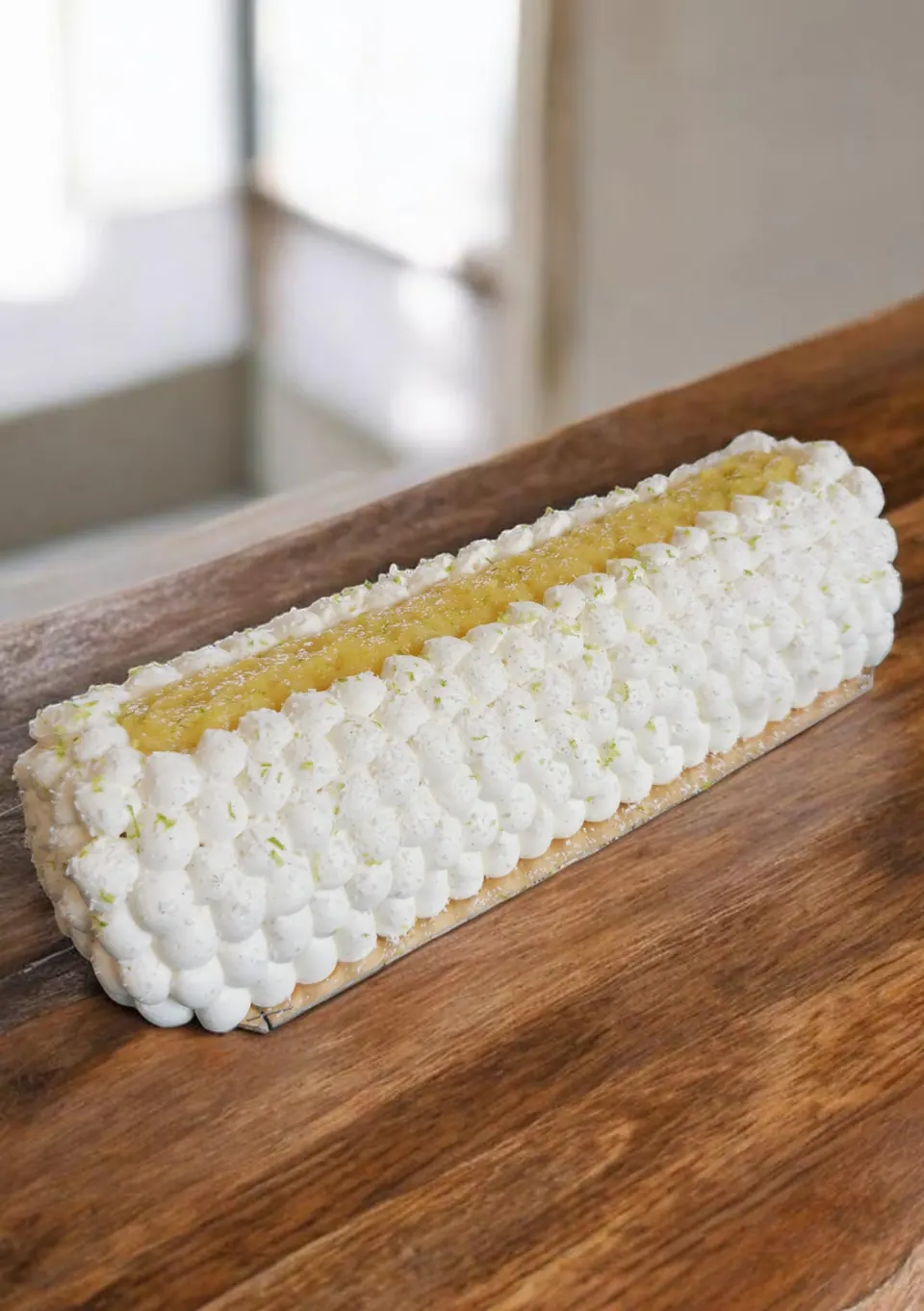 Bûche longue recouverte de perles de crème blanche et de zestes